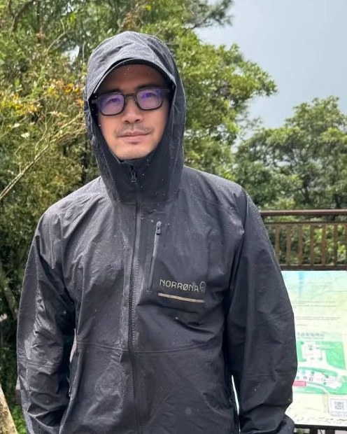 Hank Chen in a dark rain jacket on a forest trail in Taiwan